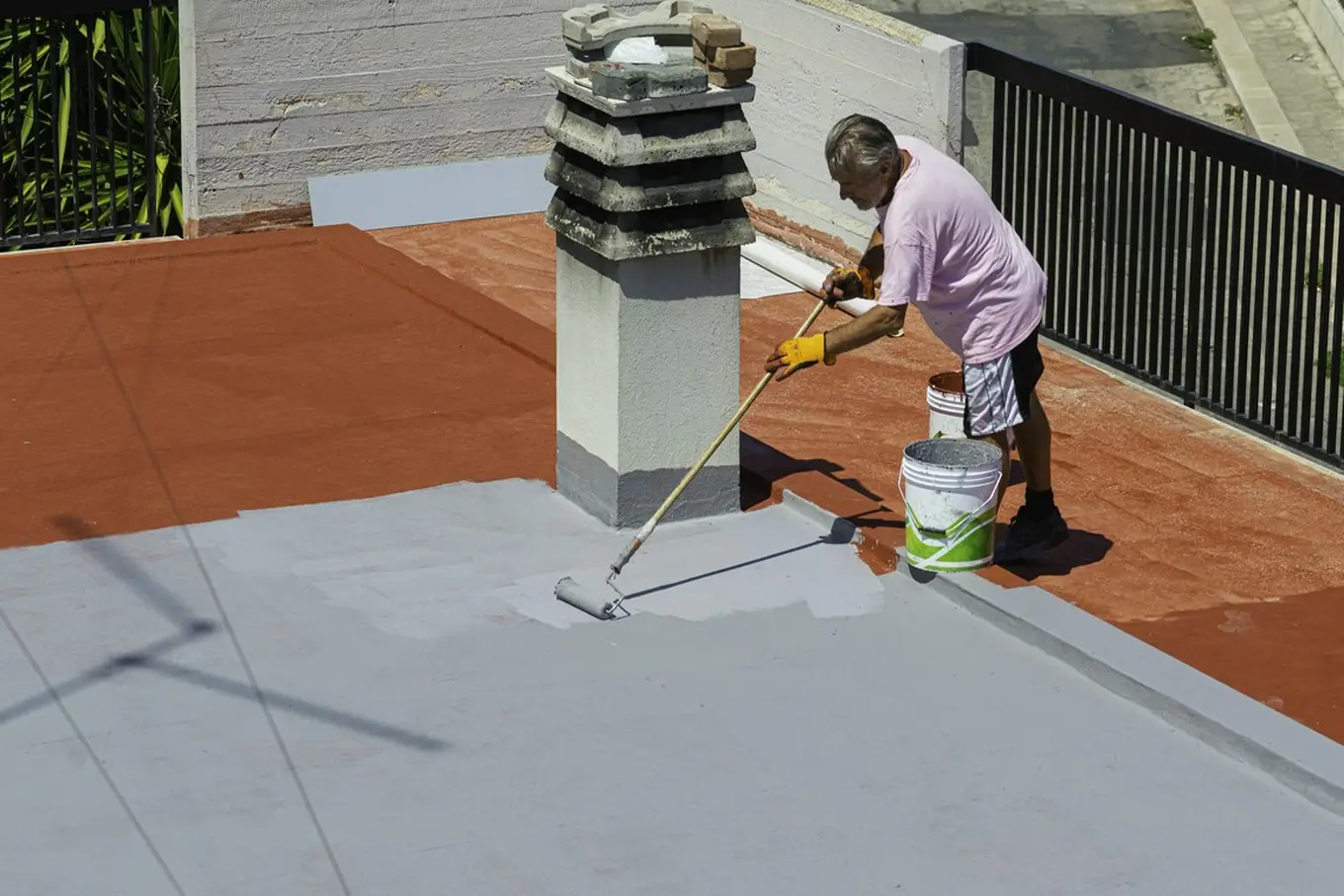 mezczyzna malujacy plaski dach - Jaką farbę wybrać do malowania dachu?